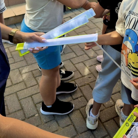Policjantka przekazuje dzieciom elementy odblaskowe podczas działań Bezpieczna Droga do Szkoły w Białymstoku. Źródło: bialystok.policja.gov.pl